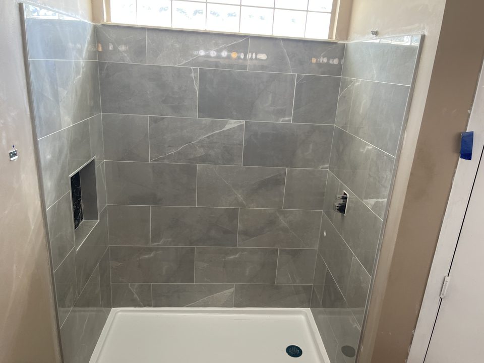 Shower wall tile installation in progress, niche and shower pan in with fixtures and trim not yet installed