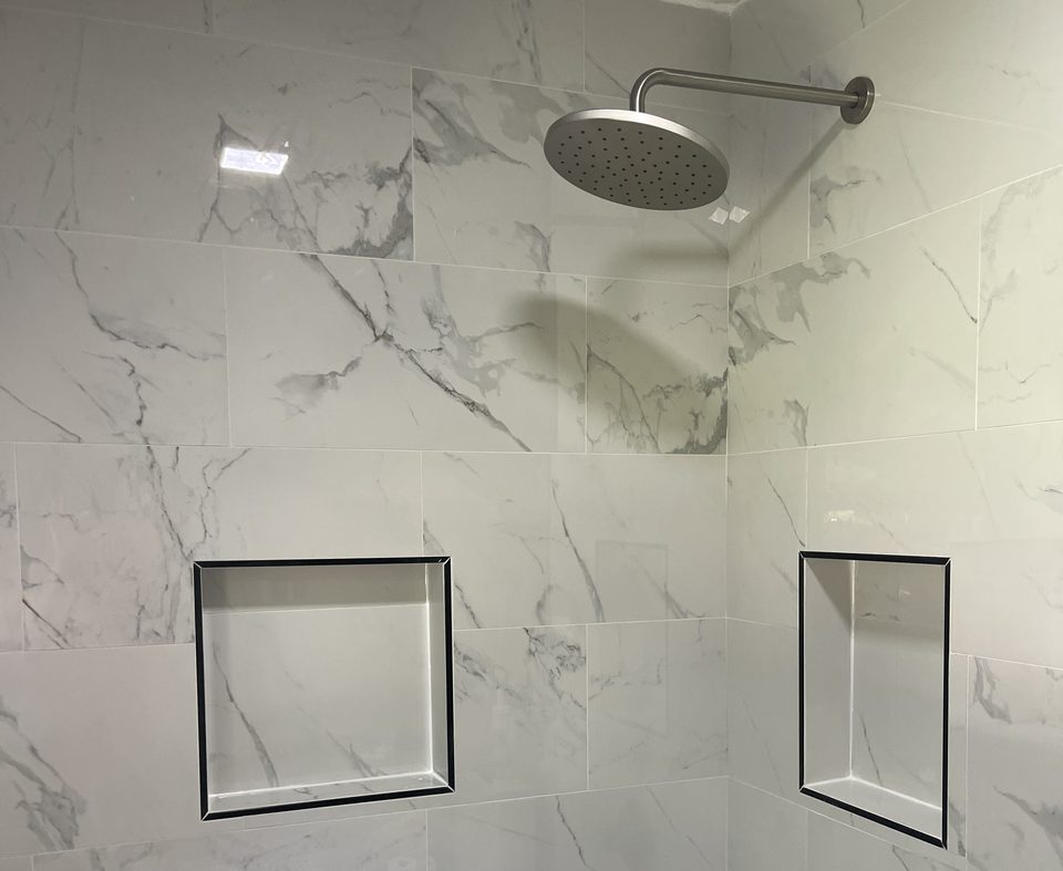 Finished bathroom shower by S&M Renovations, Mason, Ohio — newly tiled shower with rain shower head and two finished tile niches